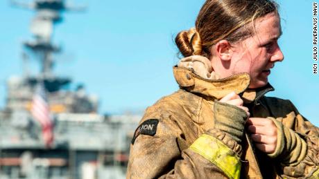 Een matroos trekt haar brandweer-ensemble uit na het bestrijden van een brand aan boord van het amfibische aanvalsschip USS Bonhomme Richard.