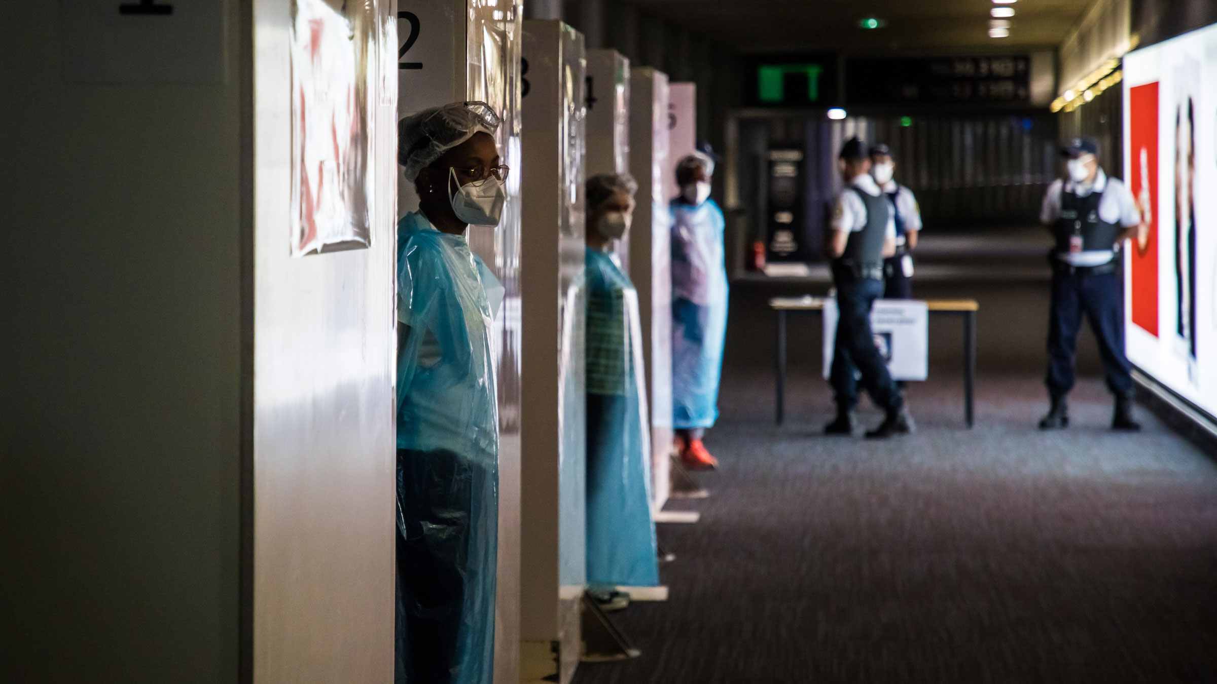 Health workers wait for incoming travelers at the Charles de Gaulle Airport outside of Paris on Friday.