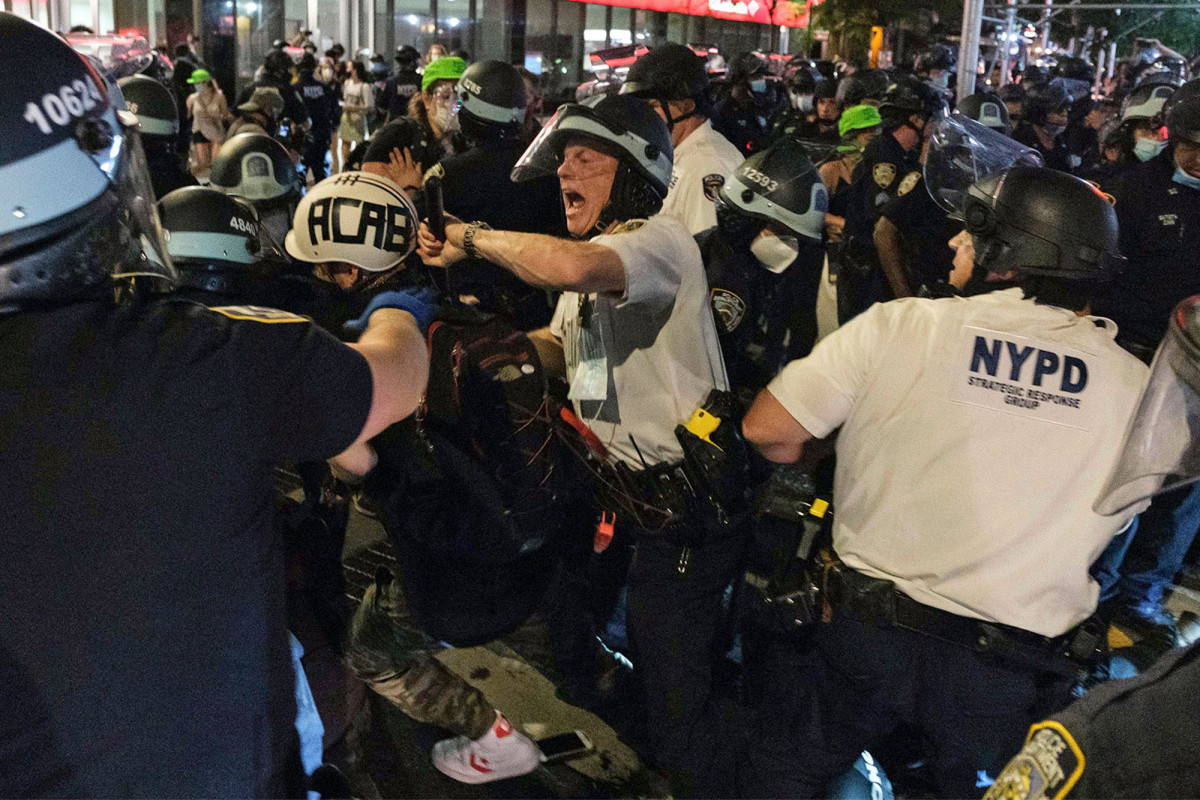 Opstandelingen richten zich op NYPD-auto’s, lichtbranden in een chaotisch stadsgezicht