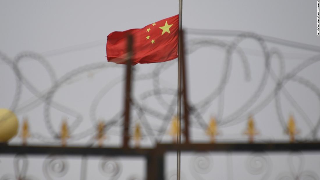 TOPSHOT - This photo taken on June 4, 2019 shows the Chinese flag behind razor wire at a housing compound in Yangisar, south of Kashgar, in China's western Xinjiang region. ( Photo by GREG BAKER/AFP/Getty Images)